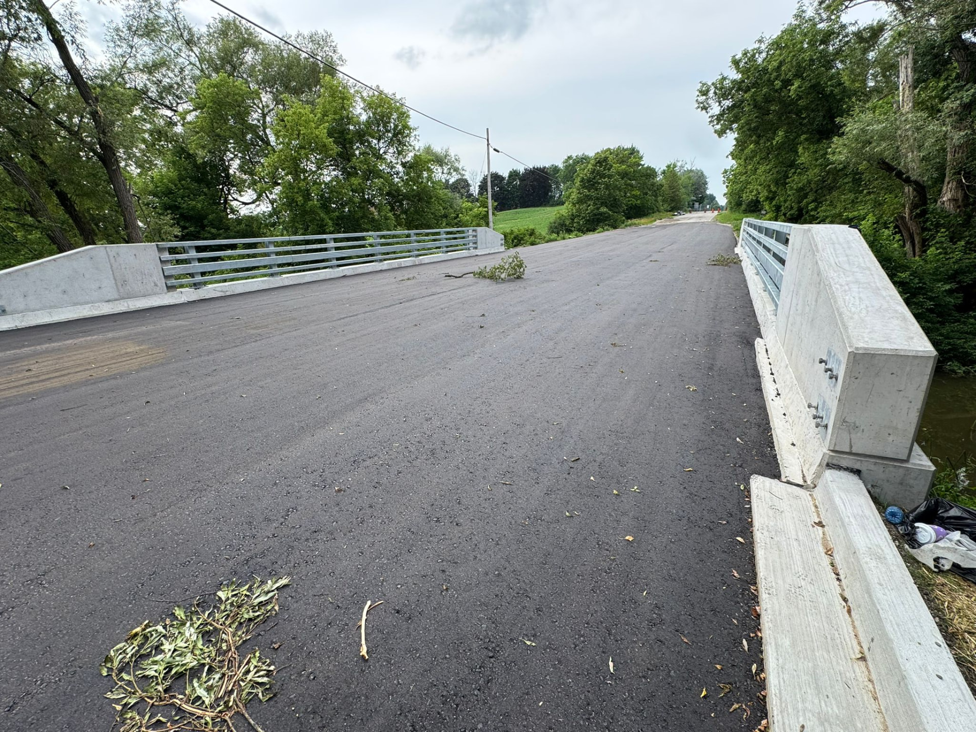 Bridge approach with new concrete barrier wall and fresh asphalt